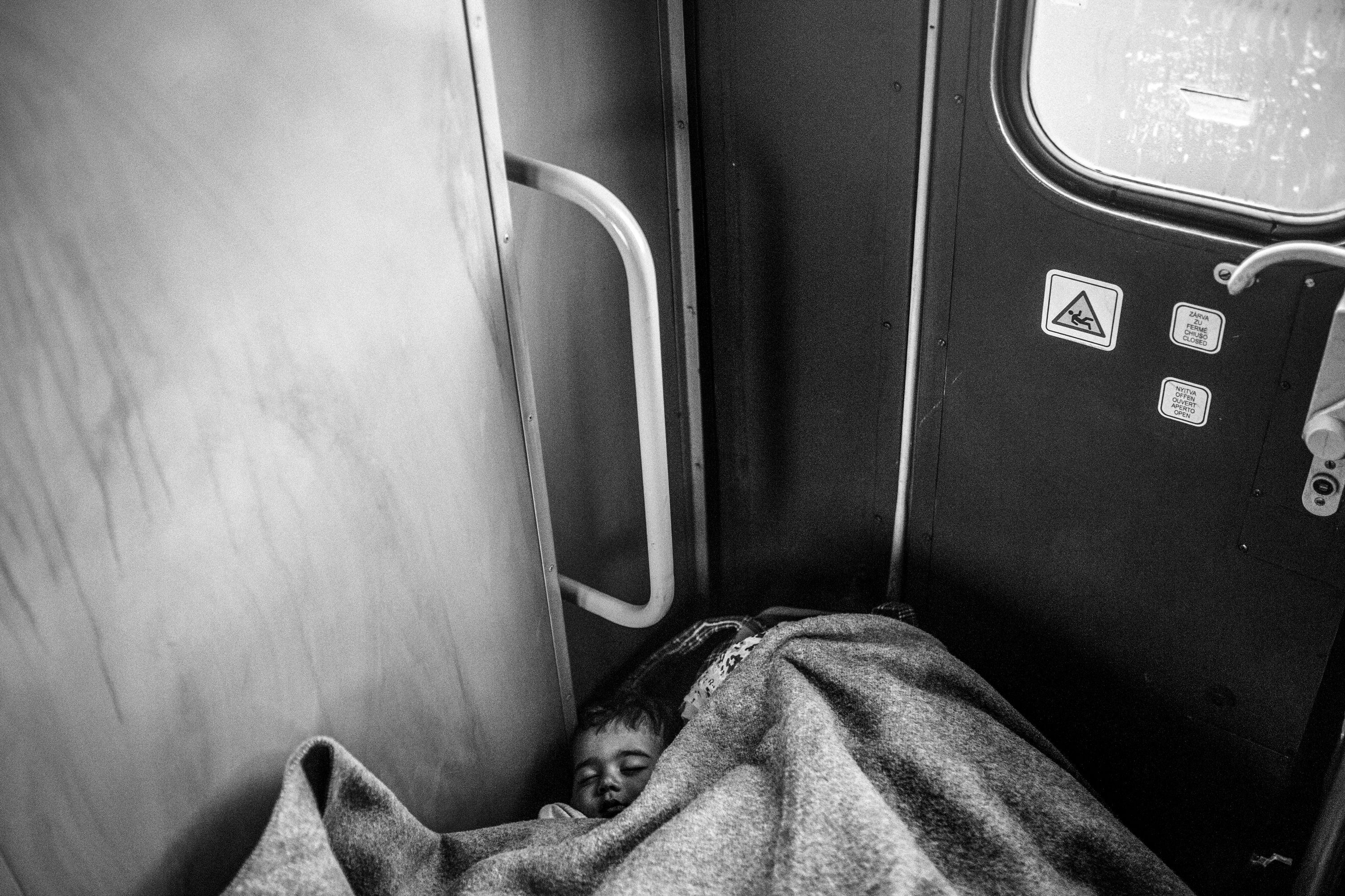 A Syrian refugee woman and her baby have no other choice but to sleep on the floor in a crowded train going to the Austrian border. Villany - Hungary, in September 2015 .